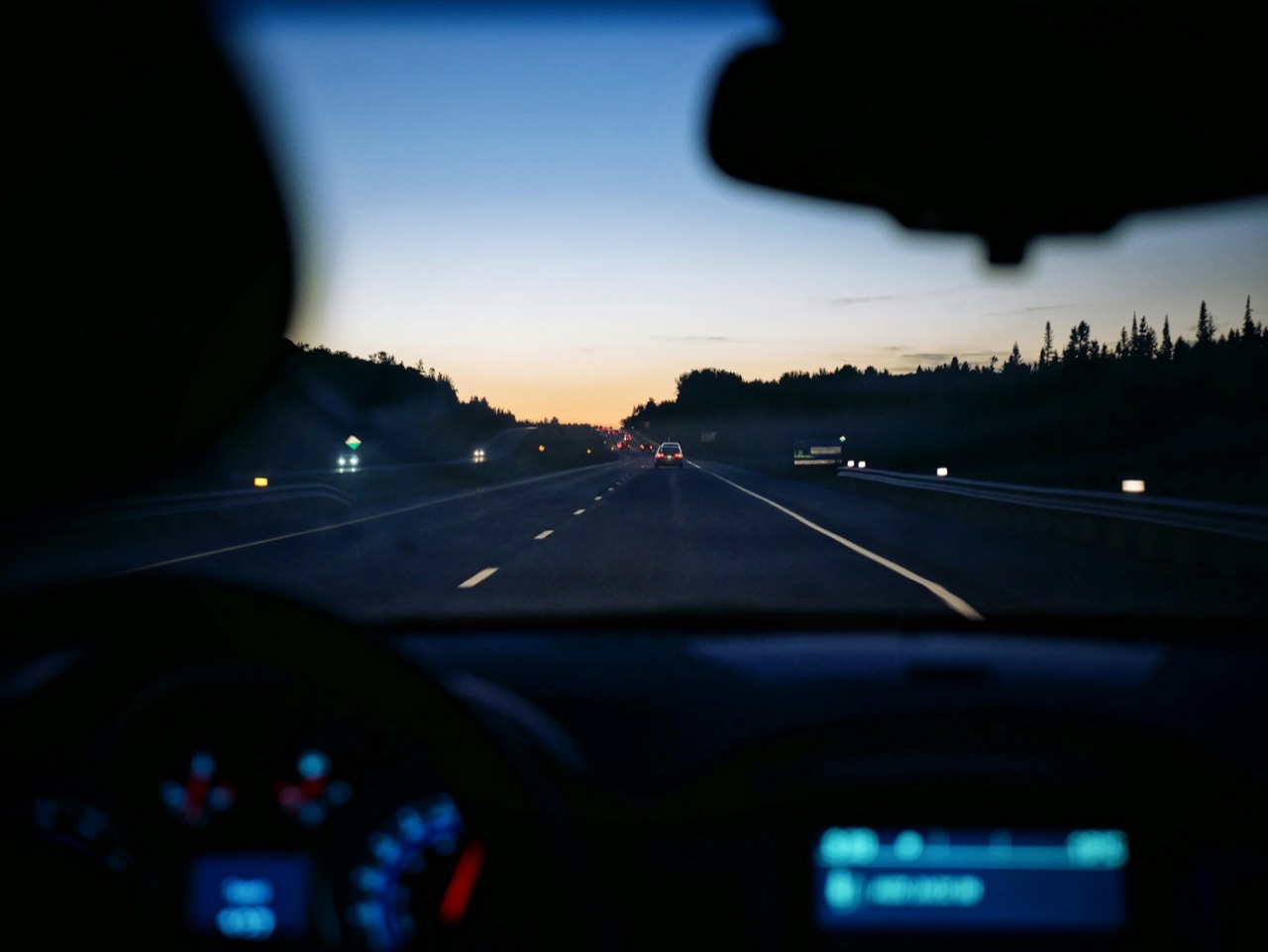 Representative view from inside a vehicle on a highway at dusk.